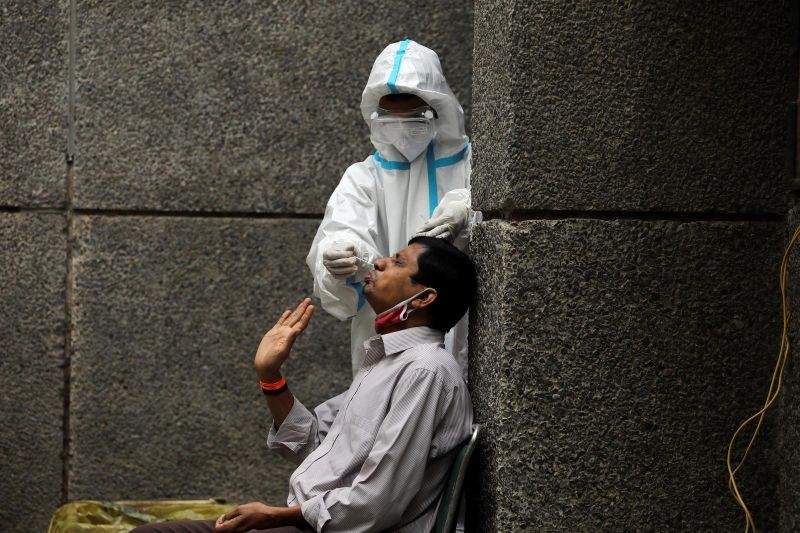 FILE PHOTO: A healthcare worker wearing personal protective equipment (PPE) collects a swab sample from a man amidst the spread of the coronavirus disease (COVID-19), at a testing center in New Delhi, India October 29, 2020. REUTERS/Anushree Fadnavis